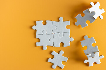 top view of unfinish white  jigsaw puzzle on yellow or orange background. empty blank plain space for copy space. 