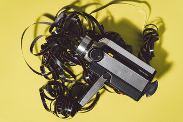 Old vintage video camera with sound with the film negative blurred on yellow background.