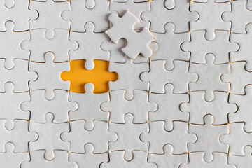Fototapeta premium top view of white unfinish jigsaw puzzle on yellow orange background. business concept.