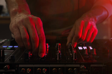 DJ creating music on modern console mixer in night club, closeup