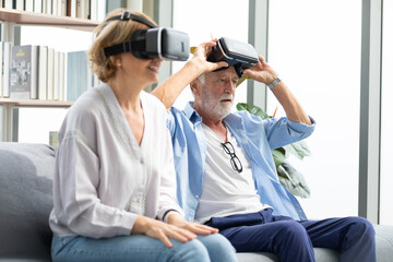 Fototapeta premium senior man wearing virtual reality headset or VR and looking something on the sofa