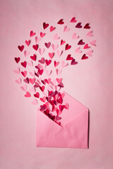 Love letters. Pink envelope with  red hearts inside on  pink background.