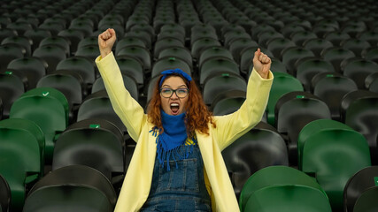 Caucasian woman cheers for a sports team at the stadium. The girl watches the match at the stadium...