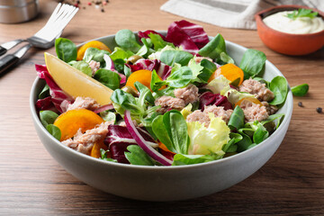Bowl of delicious salad with canned tuna and vegetables on wooden table