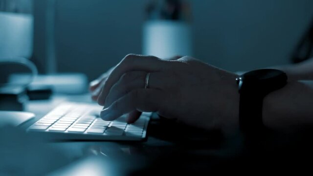 manos en teclado de noche. Escriben en las penumbras