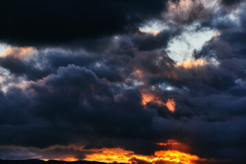 Fototapeta premium Dreamy dark sky with black, purple and orange sunset clouds, horizontal design background, stylish website backdrop