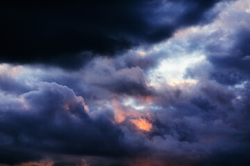 Gloomy background with purple-blue and orange sunset clouds in close-up, bad weather and stormy sky