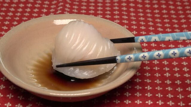 Closeup shot of dipping dim sum shrimp dumplings in the sauce with chopsticks. Har Gow, Chinese crystal prawn dumpling. 4K