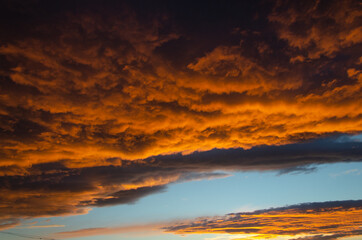 Lush, heavy clouds, painted orange by the sun at sunset. Texture.