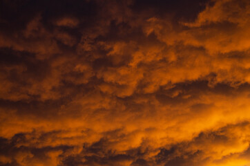 Lush, heavy clouds, painted orange by the sun at sunset. Texture.
