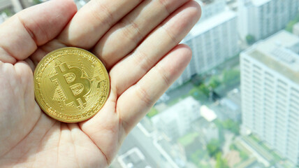 Holding Bitcoin on Hand, background of Tokyo Aerial
