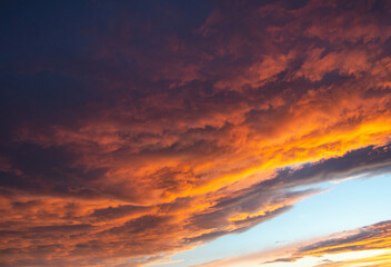 Lush, heavy clouds, painted orange by the sun at sunset. Texture.