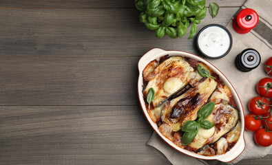 Delicious eggplant lasagna in baking dish on wooden table, flat lay. Space for text