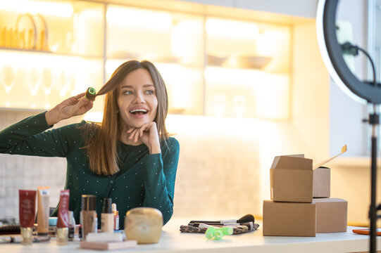 Smiling young woman demonstrating hairstyling tips