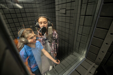 Young singers singing into the mike in the recording studio