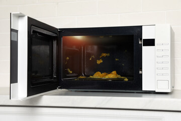 Dirty microwave oven on white countertop indoors