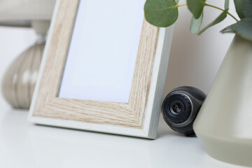 Small camera hidden among home stuff on white table