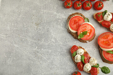 Delicious sandwiches with mozzarella, fresh tomatoes and basil on light grey table, flat lay. Space for text