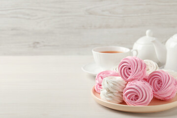Delicious zephyrs served with tea on white wooden table, space for text