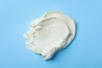 Smear of delicious cream cheese on light blue background, top view