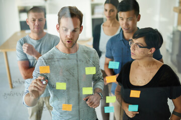 Planning is the first step. Cropped shot of a group of young designers planning on a glass board.