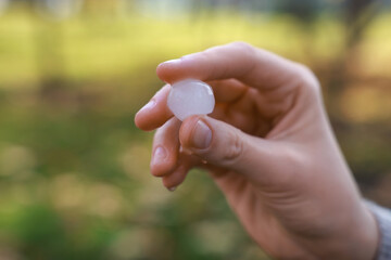 Woman holding hail grain after thunderstorm outdoors, closeup