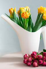 bunch of yellow tulips in a white bailer and pink roses, gardening or holiday concept, copy space