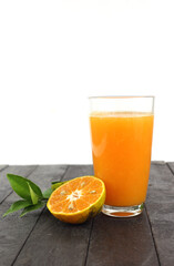 Glass of fresh and delicious orange juice on black table against white background
