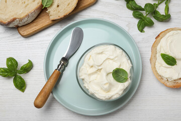 Tasty cream cheese with basil and fresh bread on white wooden table, flat lay