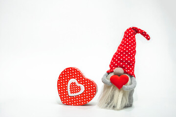 Leprechaun in a red hat with a red heart in his hands and a gift box isolated on a white background. Idea valentine's day