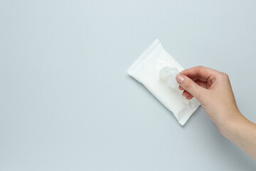 Woman taking wet wipe from pack on light background, top view. Space for text