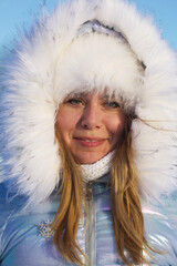 Portrait of a girl in winter clothes. Woman posing on a walk in a winter park. Facial portrait.