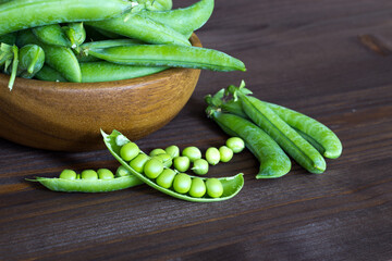 Pods of green peas in a wooden bowl. Seasonal products. Products from local producers. Vegetarianism. copy space. Close-up. Selective focus. - 481307437