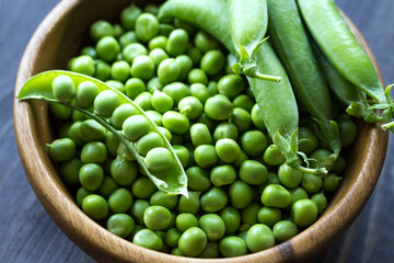 Green peas in a wooden bowl. Seasonal products. Products from local producers. Vegetarianism. Close-up. Selective focus. - 481307452