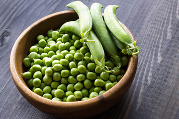 Green peas in a wooden bowl. Seasonal products. Vegetarianism. Close-up. Selective focus. - 481307471
