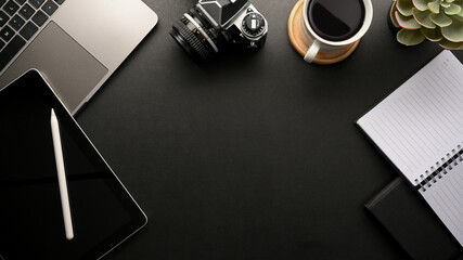 Modern black workspace with a copy space, digital devices and supplies.