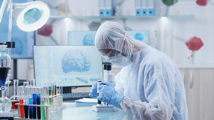 Fototapeta premium Specialist researcher doctor analyzing blood sample using medical microscope working at illness diagnosis during chemistry experiment in microbiology hospital laboratory. Medicine concept