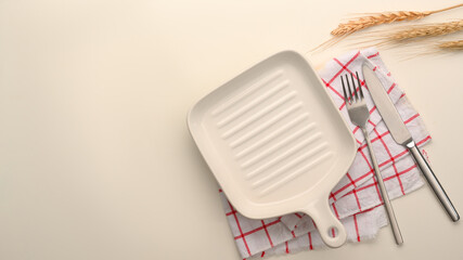 Stylish white plate with fork and knife over striped kitchen towel