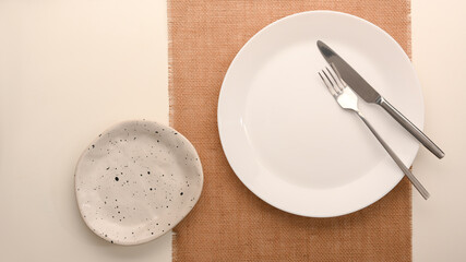 Simple minimal white plate with silverware over placemat