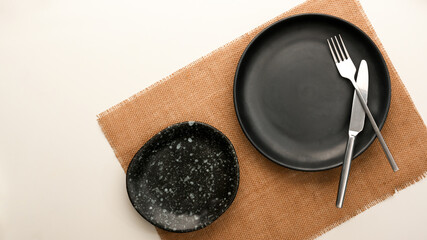 Obraz na płótnie Canvas Empty patterned black plate, silverware on white table.