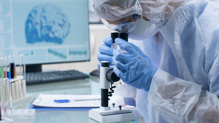 Closeup of scientist doctor researcher wearing ppe equipment analyzing blood sample using medical...