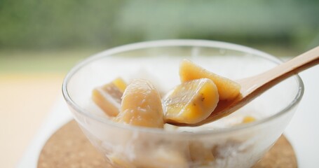 Close up wooden spoon holding Thai traditional sweet dessert food banana in coconut milk, Thai Cuisine	
