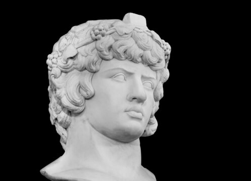 Gypsum copy of famous ancient statue Antinous head isolated on a black background. Plaster antique sculpture young man face. Renaissance epoch. Portrait