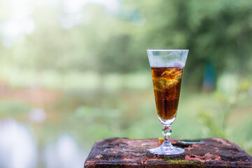 Cola in the glass over sunlight and natural green background cola in a glass with ice