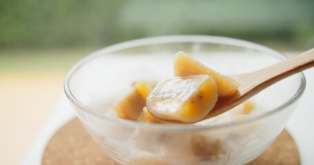 Close up wooden spoon holding Thai traditional sweet dessert food banana in coconut milk, Thai Cuisine	
