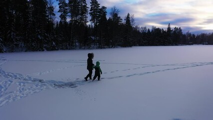 Mother and Son Explore Winter Outdoors Walking Across Frozen Snow Covered Lake Footprints at Sundown