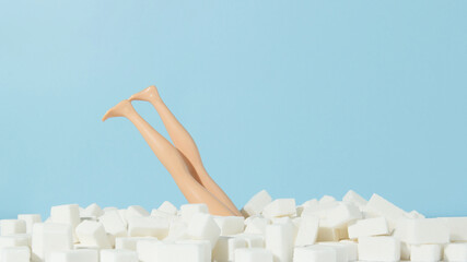 Female doll diving in sugar cubes. Stop sugar adiction concept. - obrazy, fototapety, plakaty