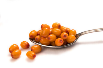 A spoon filled with an orange sea buckthorn berry isolated on a white background close-up. A portion of berries.