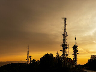 Telecommunication antenna towers with sunset on background. Communication, networks and technology concept.