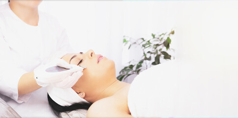 Banner- long format. Female specialist doing facial for woman undergoes dermatologic procedures...